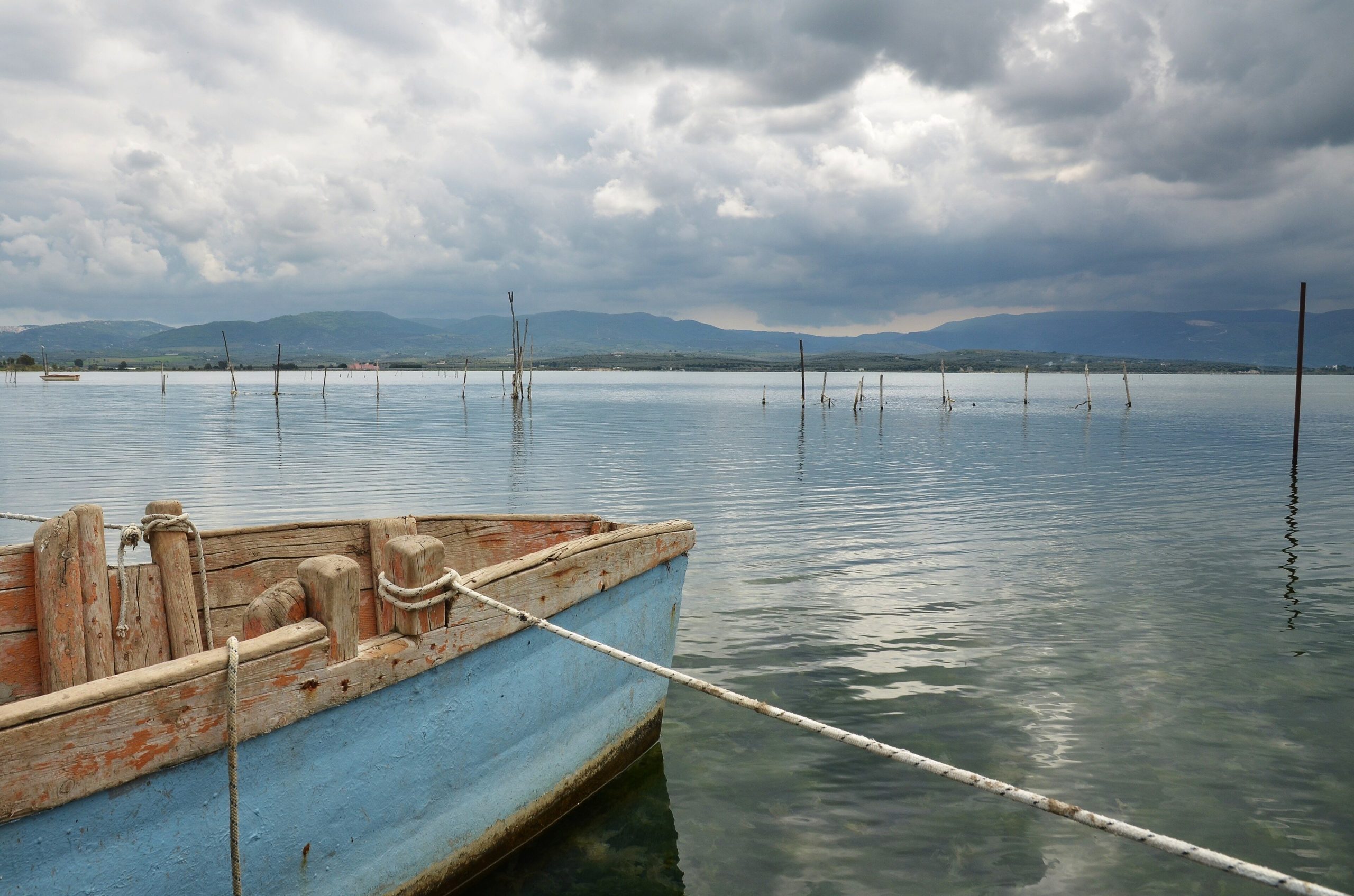 Barca sulla riva del lago di Varano con i pali della pesca e il Gargano sullo sfondo